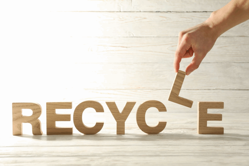 Person arranging the word “recycle” with wooden letters.
