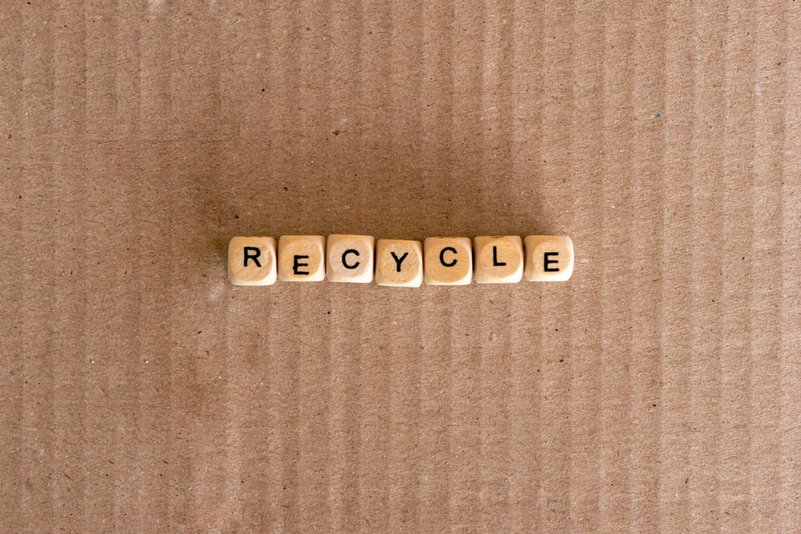Word “recycle” on wooden cubes on a cardboard background.